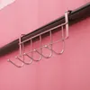 A close-up shot of a silver metal over-the-door hook rack with multiple hooks, hanging on a dark rod against a pink wall. Voir les images du produit