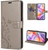 A collage of images showing a flip phone case for a ZTE Blade V70 Vita in gray, with floral and butterfly embossing. One image shows the case open with cards and cash inserted, another shows the phone inside the case in a landscape orientation. Produktbild-Vorschau