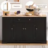 A black sideboard with a wooden top, decorated with fruit and coffee maker, set against a white paneled wall. Produktbild-Vorschau