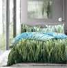 A bed with a green and blue patterned duvet cover and pillows, set in a room with a large window and abstract art on the wall. Náhled obrázku produktu