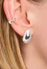 Close-up of a person's ear wearing silver hoop earrings and a silver ear cuff. Anteprima dell’immagine prodotto