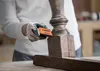 A person is sanding an old wooden table leg with a Bosch sanding block. Produktbild-Vorschau