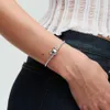 A woman's arm wearing a silver bracelet with a Mickey Mouse charm. Podgląd zdjęcia produktu