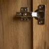 A close-up view of a cabinet hinge on a wooden surface. Anteprima dell’immagine prodotto