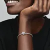 A close-up shot of a person's wrist wearing a Pandora bracelet with a heart-shaped charm. Podgląd zdjęcia produktu