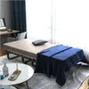A foldaway bed with a mattress and blue blanket, set up in a room with a desk and computer. Voir les images du produit