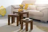 A living room scene with a sofa, pillows, and a set of wooden nesting tables. Produktbild-Vorschau