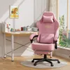 A pink gaming chair is shown next to a desk with office supplies and a painting on the wall, with a window in the background. Podgląd zdjęcia produktu