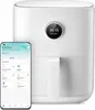A white Xiaomi Mi Smart Air Fryer is shown next to a smartphone displaying the Mi Home app. Podgląd zdjęcia produktu