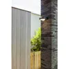 An outdoor wall light mounted on a brick pillar next to a wooden fence. Produktbild-Vorschau