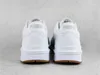 The back view of a pair of white Puma sneakers with brown soles, placed on a light gray textured surface. Produktbild-Vorschau