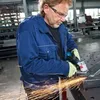 A man is using an angle grinder in a workshop. Produktbild-Vorschau