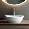 A modern bathroom sink with a faucet and a lit mirror in the background. Produktbild-Vorschau