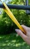 A hand holding a yellow resistance band wrapped around a metal bar outdoors. Náhľad obrázku produktu