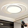 A hand holding a remote control points it towards a modern LED ceiling light fixture. Produktbild-Vorschau
