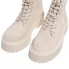 A close-up, studio shot of a pair of beige suede lace-up boots with thick platform soles, presented against a white background. Produktbild-Vorschau