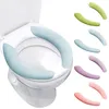 A toilet seat with light blue covers and several colorful toilet seat covers displayed next to it. Produktbild-Vorschau