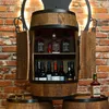 A wooden barrel-shaped cabinet filled with bottles of alcohol, set against a brick wall. Náhled obrázku produktu