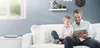 A father and son are sitting on a couch, looking at a tablet. Anteprima dell’immagine prodotto
