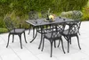 A garden dining set with chairs and a table on a patio, surrounded by greenery. Náhled obrázku produktu