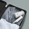A travel steamer is placed inside an open suitcase next to a folded suit jacket and a t-shirt. Produktbild-Vorschau