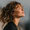A woman with her eyes closed and head tilted back, wearing earbuds. Podgląd zdjęcia produktu