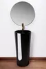 A black pedestal sink with a round mirror above it, set against a white wall. Produktbild-Vorschau