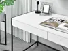 A close-up view of a white desk with black legs, featuring an open magazine and a decorative picture frame. Voir les images du produit
