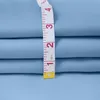 A close-up of folded light blue fabric with a measuring tape laid across it. Produktbild-Vorschau