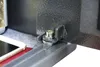 A close-up view of a metal bracket and bolt assembly on a gray textured surface, with a smartphone and a red object visible in the background. Anteprima dell’immagine prodotto