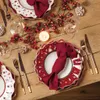 A Christmas-themed table setting with plates, napkins, cutlery, glasses, and festive decorations. Produktbild-Vorschau