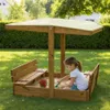 A young girl playing in a wooden sandbox with a canopy. Podgląd zdjęcia produktu