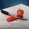 A knife slicing a tomato on a brushed metal surface. Produktbild-Vorschau