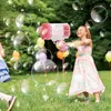 Pink-weiße Bazooka-Blasenpistole, gehalten von einem lächelnden Mädchen in einem gestreiften Kleid, umgeben von Blasen in einem grasigen Park Voir les images du produit