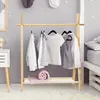 A child's bedroom with a wooden clothes rack holding children's clothes and a rolled-up blanket on the shelf. Produktbild-Vorschau