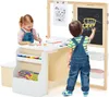 Two young children are actively engaged with a wooden easel and art station, one drawing on paper and the other on a chalkboard. Produktbild-Vorschau
