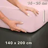Hands are shown adjusting a pink fitted sheet on a mattress. Produktbild-Vorschau