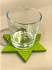 A clear glass votive holder with snowflake etching sits on a green, star-shaped felt coaster. Produktbild-Vorschau