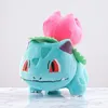 A plush toy of the Pokemon character Bulbasaur with a pink flower bud on its back, placed on a marble surface. Produktbild-Vorschau