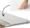 A hand pressing down on a mattress topper, with a cutaway view showing the layers of the topper. Produktbild-Vorschau