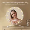 A woman is holding a cosmetic product in front of a lighted makeup mirror. Produktbild-Vorschau