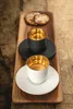 Two espresso cups with gold interiors and saucers are placed on a wooden tray, with two cookies in the background. Náhled obrázku produktu