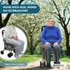 An elderly woman sitting on a rollator walker in a park with blooming trees. Produktbild-Vorschau
