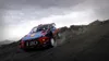 A rally car driving on a dirt track with a cloudy sky. Produktbild-Vorschau