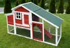 A red and white chicken coop with a green roof sits on a green lawn, with trees in the background. Produktbild-Vorschau