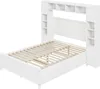 A white bed frame with a headboard featuring multiple shelves and two side cabinets, shown from a slightly elevated diagonal angle. Produktbild-Vorschau