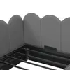 Close-up view of a grey upholstered bed frame with a scalloped headboard and metal slats. Produktbild-Vorschau