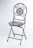 A brown metal folding chair with intricate scrollwork on the backrest and a patterned seat, displayed against a white background. Podgląd zdjęcia produktu