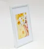 A white picture frame with a portrait of a woman adorned with flowers. Produktbild-Vorschau