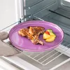 A plate of food, including meat and vegetables, is placed on a rack inside an oven. Náhled obrázku produktu